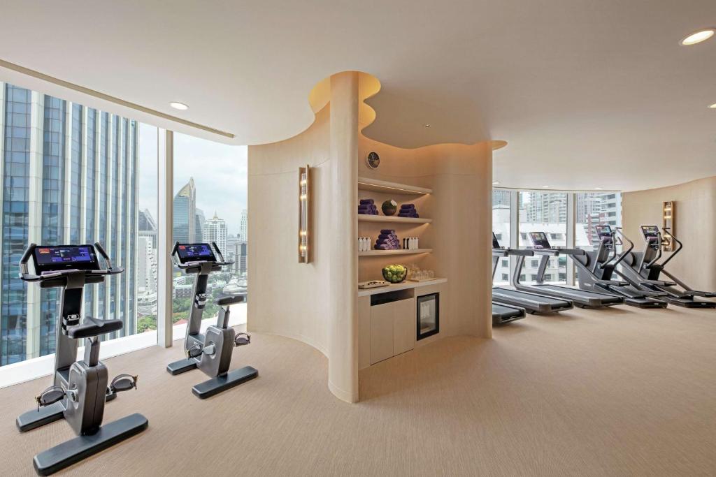 A bright high-floor fitness room with cardio equipment and skyline views.