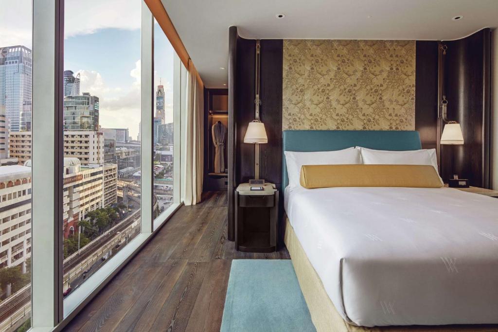 A bedroom with a patterned headboard and wall-to-wall city glazing.