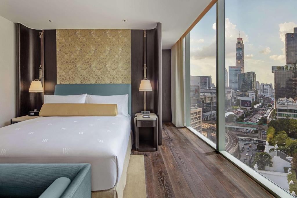 A bed positioned beside floor-to-ceiling windows over the city.