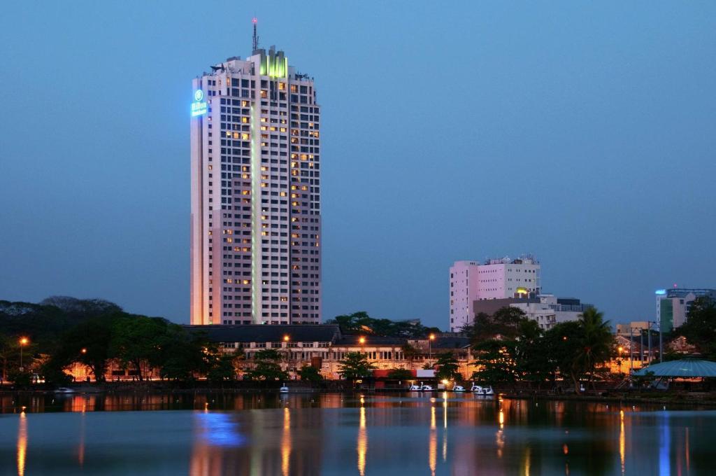 a city skyline with a tall building at night at Hilton Colombo Residence in Colombo