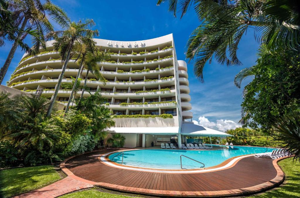 a hotel with a swimming pool in front of a building at Hilton Cairns in Cairns