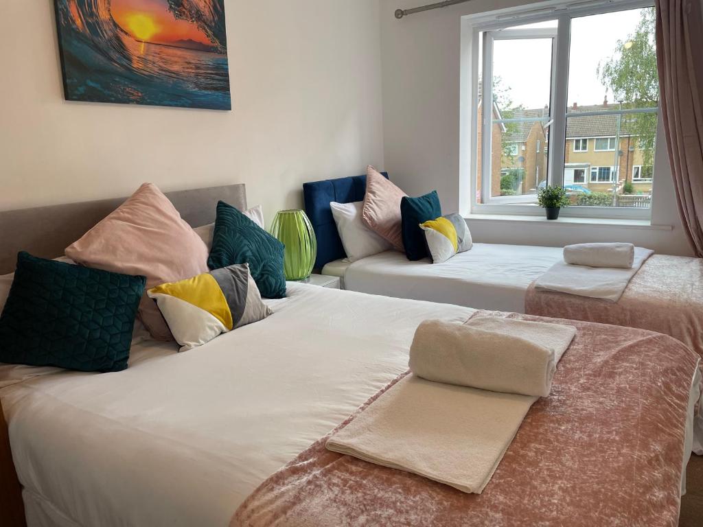 a room with two beds with pillows and a window at Mayfair - Duplex Relocations in Wakefield