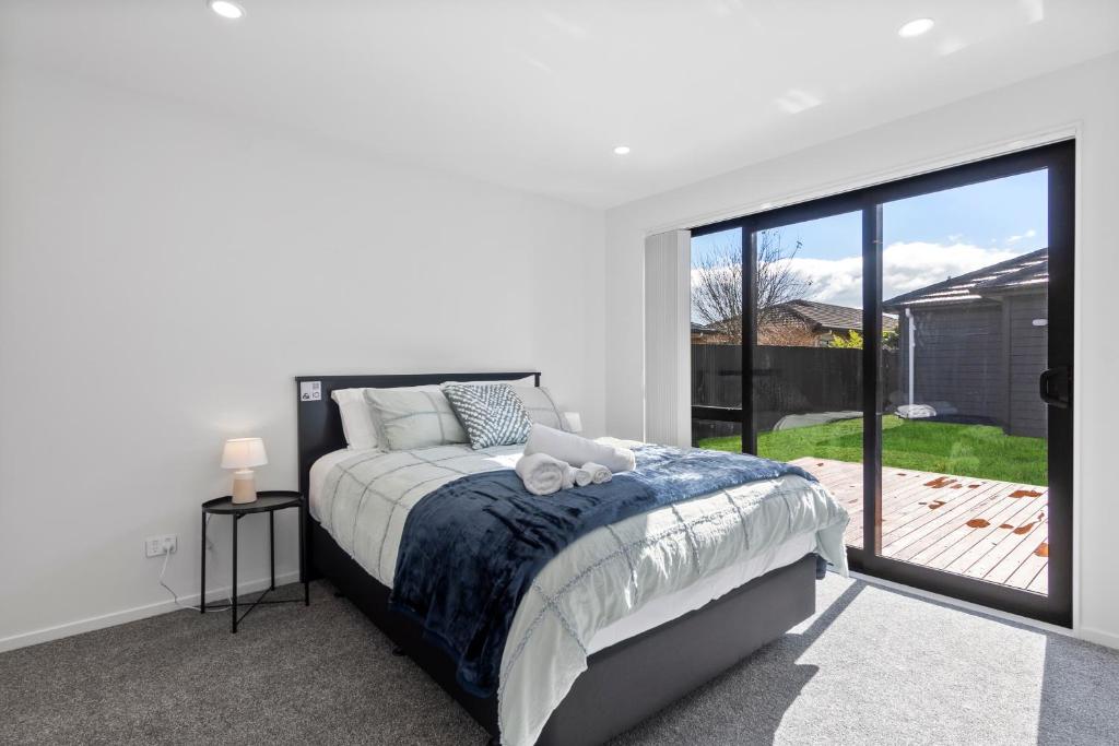 a bedroom with a bed and a large sliding glass door at New 3bds house walk to Rototuna shopping Centre in Hamilton