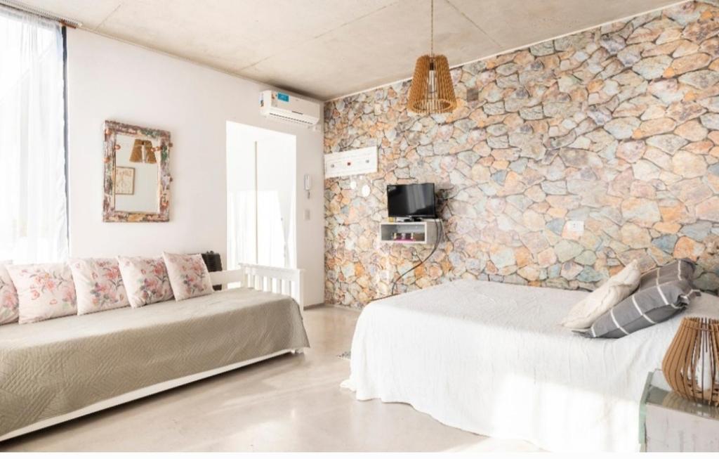 a bedroom with two beds and a stone wall at Luminoso y comfortable monoambienteA 25 minutos de Ezeiza in Remedios de Escalada