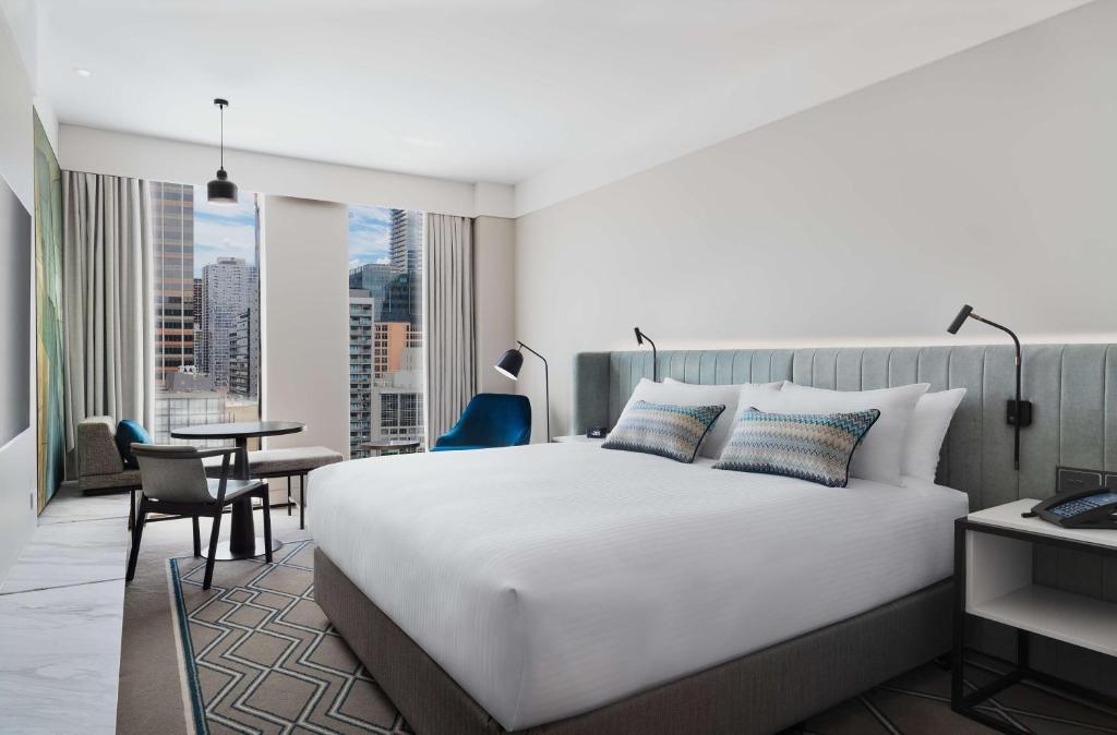ein Schlafzimmer mit einem großen weißen Bett und einem Tisch in der Unterkunft Hilton Melbourne Little Queen Street in Melbourne