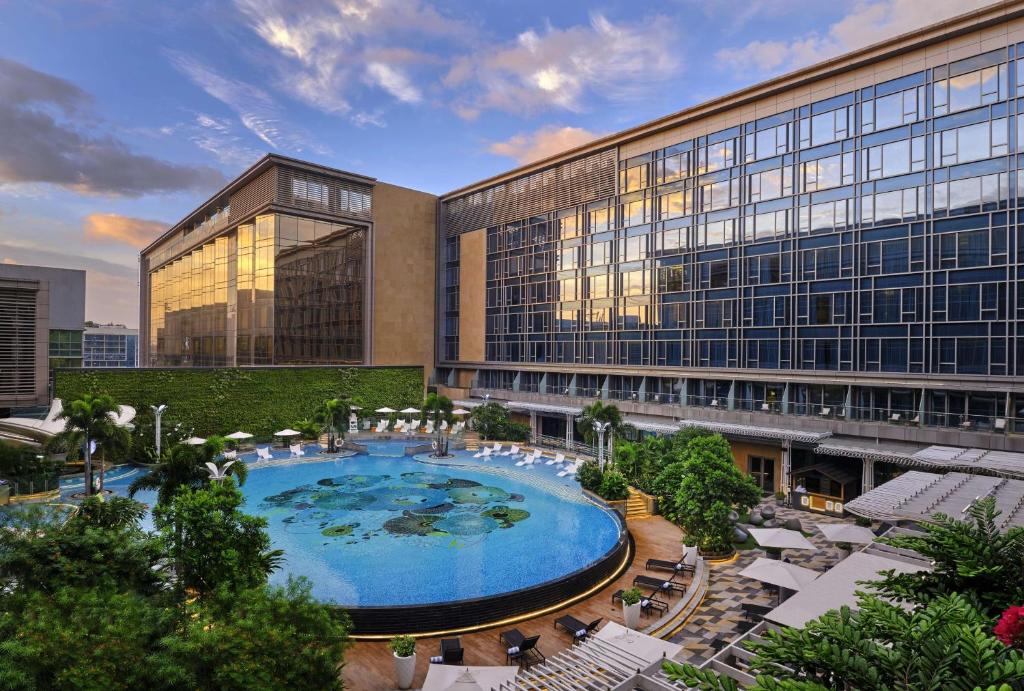 ein großes Gebäude mit einem großen Pool davor in der Unterkunft Hilton Manila in Manila