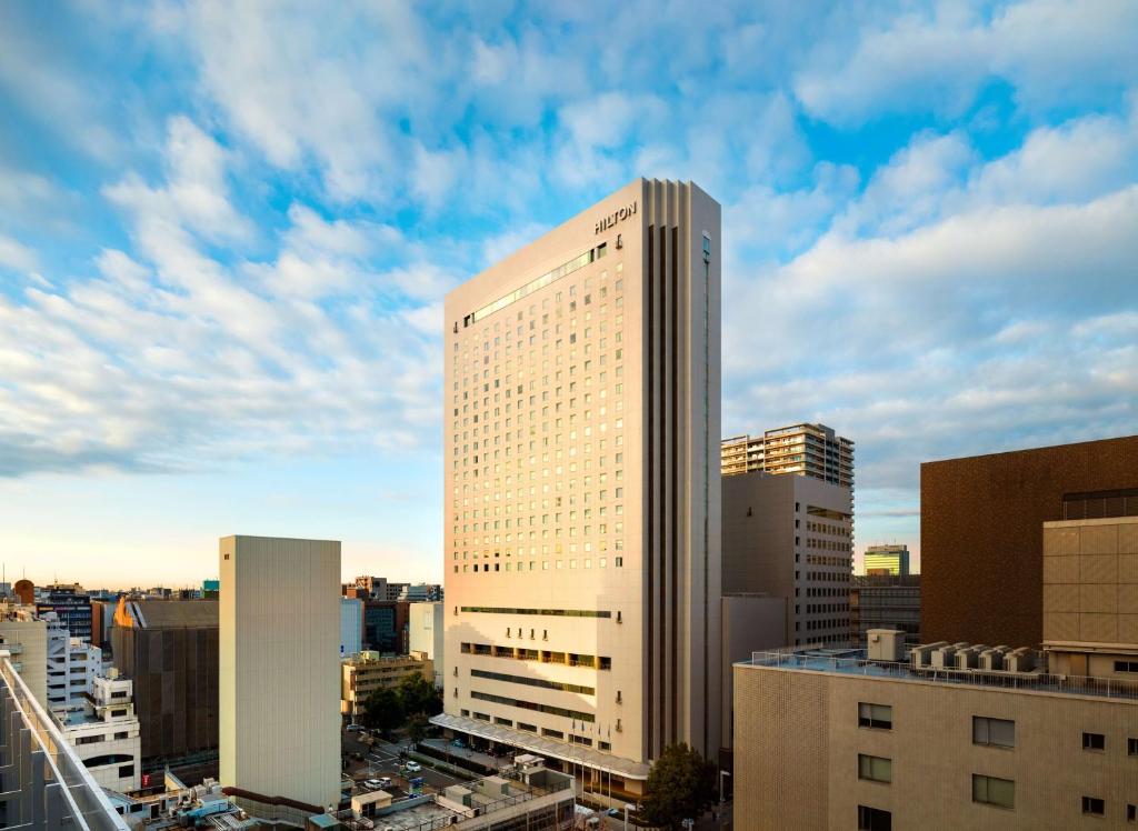 a tall white building in a city at Hilton Nagoya Hotel in Nagoya