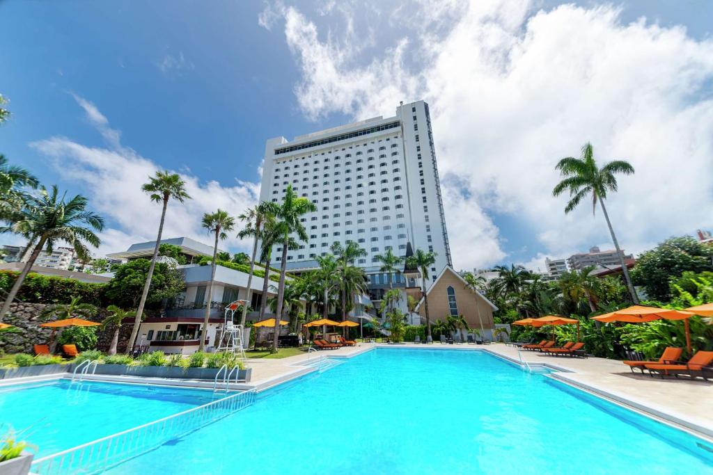 那霸DoubleTree by Hilton Naha Shuri Castle的一座高楼前的大型游泳池