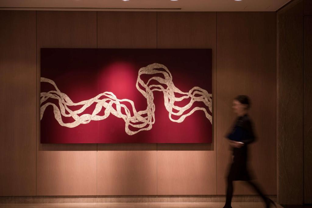a woman walking past a painting of an octopus at Hilton Osaka Hotel in Osaka