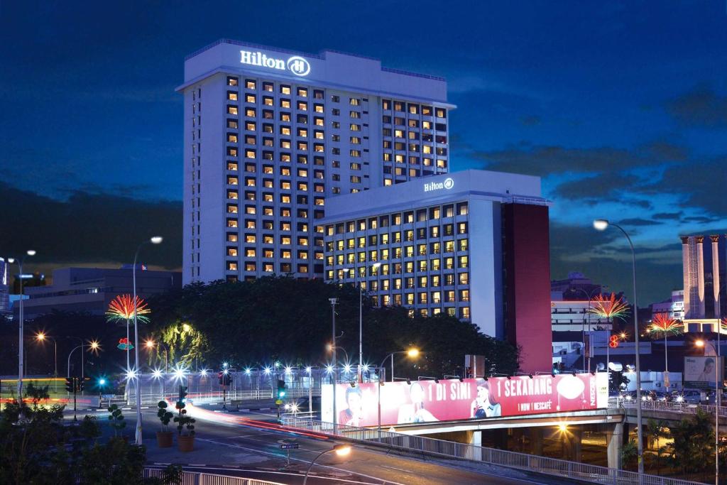 un grand bâtiment avec un panneau la nuit dans l'établissement Hilton Petaling Jaya, à Petaling Jaya