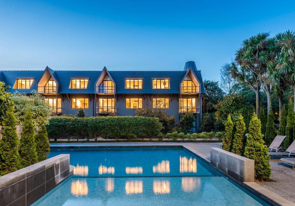 an estate with a swimming pool in front of a house at Chateau On The Park - Christchurch, A Doubletree By Hilton in Christchurch