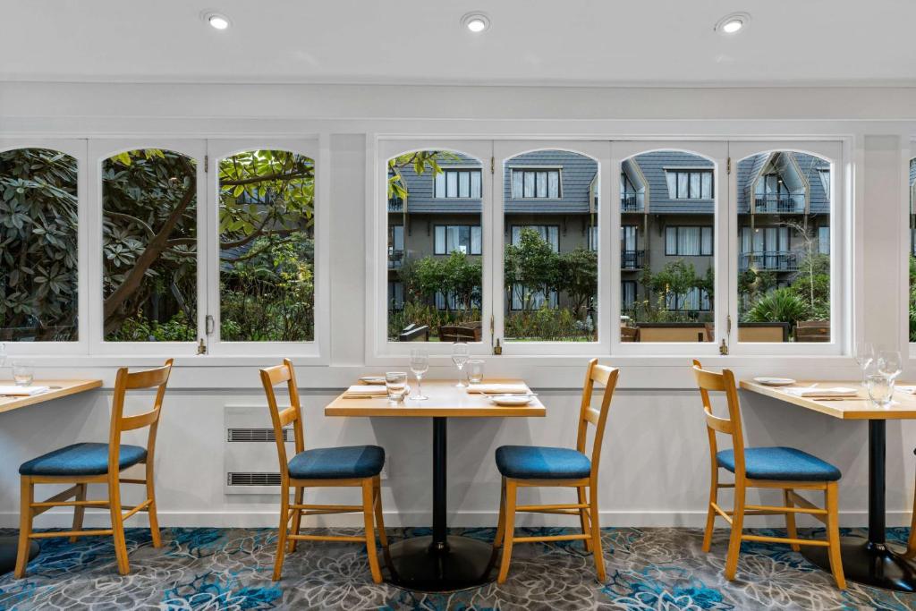 a restaurant with tables and chairs and windows at Chateau On The Park - Christchurch, A Doubletree By Hilton in Christchurch