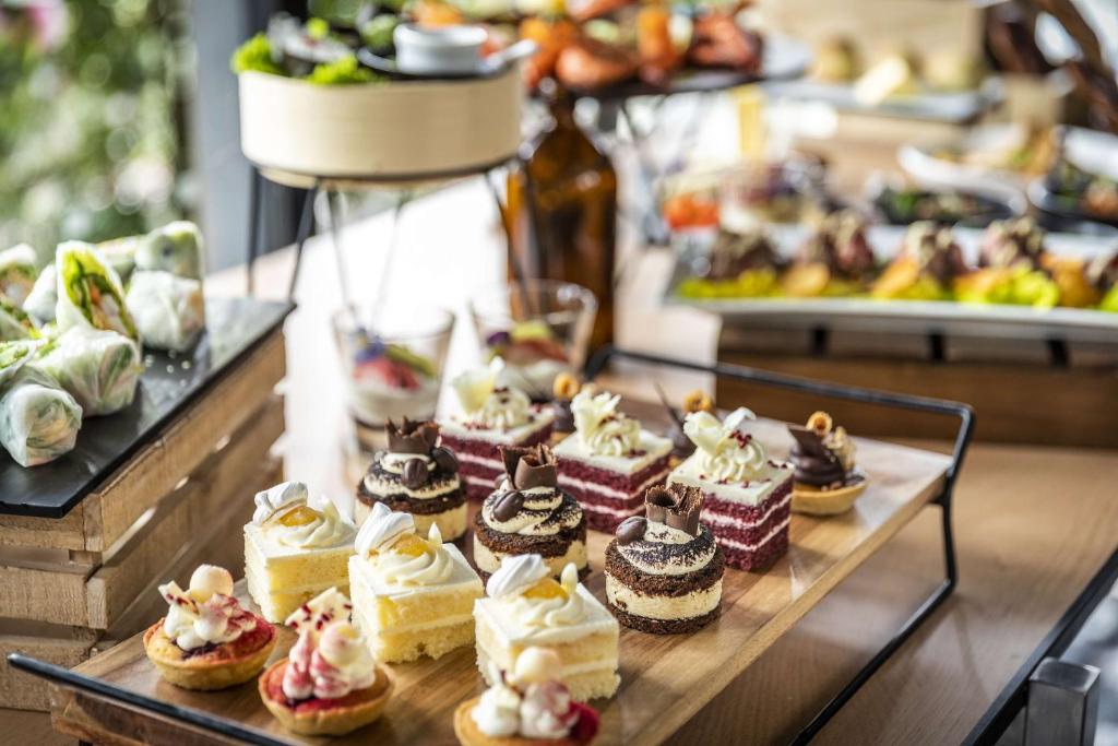 a table topped with different types of cakes and pastries at Chateau On The Park - Christchurch, A Doubletree By Hilton in Christchurch