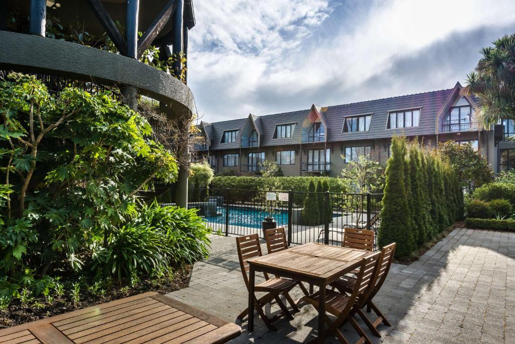 a wooden table and chairs in front of a building at Chateau On The Park - Christchurch, A Doubletree By Hilton in Christchurch