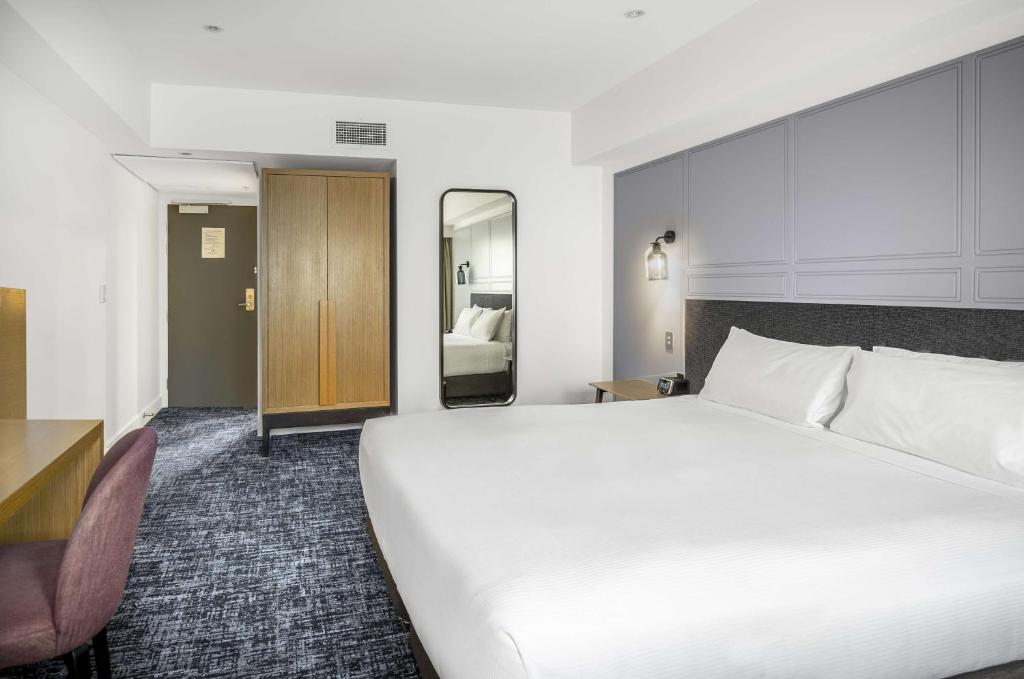 a large white bed in a hotel room at Chateau On The Park - Christchurch, A Doubletree By Hilton in Christchurch