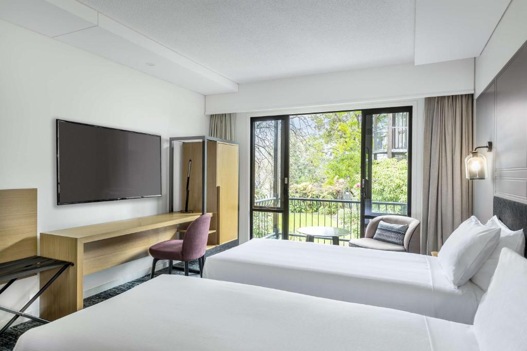 a hotel room with two beds and a flat screen tv at Chateau On The Park - Christchurch, A Doubletree By Hilton in Christchurch