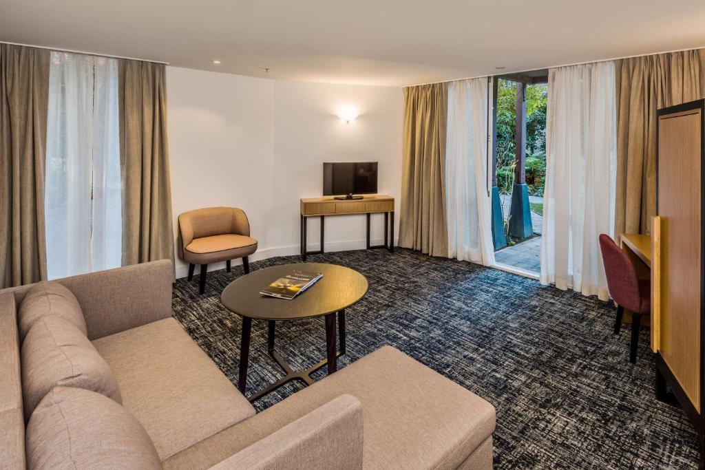 a living room with a couch and a table and a television at Chateau On The Park - Christchurch, A Doubletree By Hilton in Christchurch