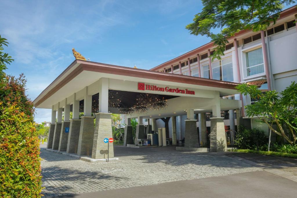 un bâtiment avec une enseigne devant lui dans l'établissement Hilton Garden Inn Bali Ngurah Rai Airport, à Kuta