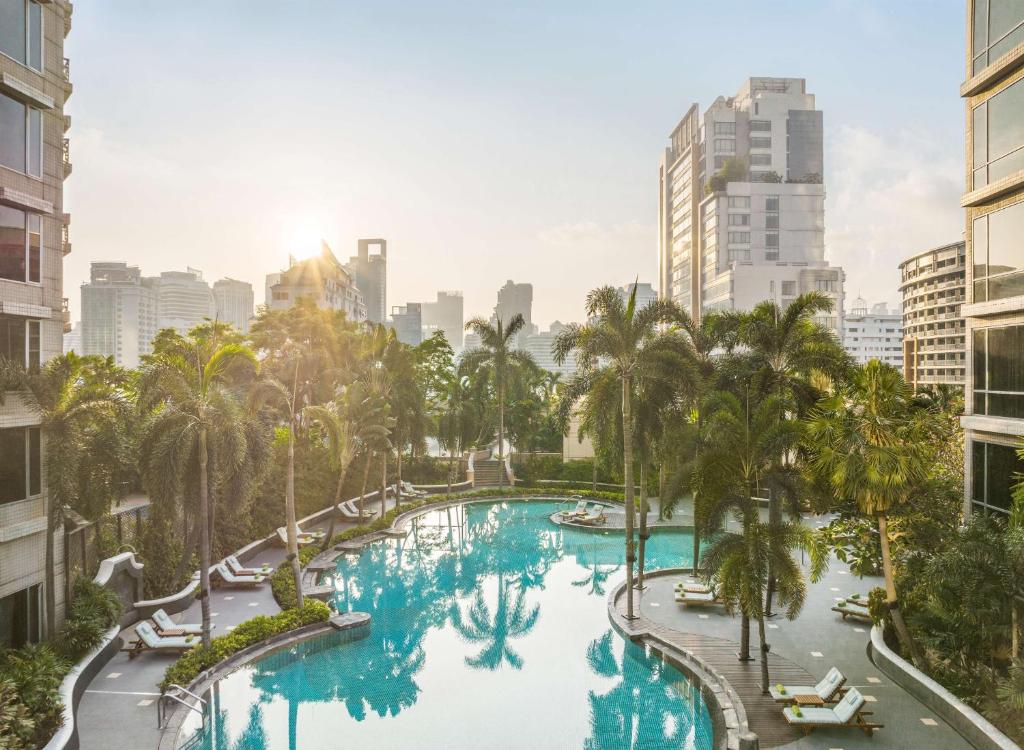 an aerial view of a large pool with palm trees and buildings at Conrad Bangkok in Bangkok