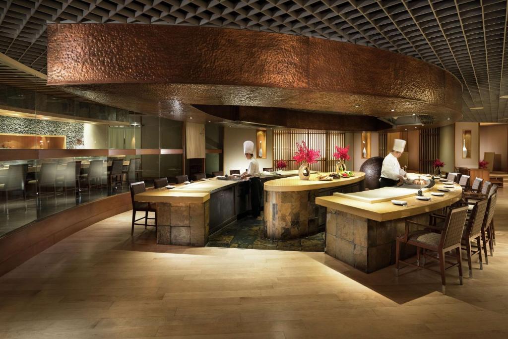 a restaurant with a bar with tables and chairs at Conrad Bangkok in Bangkok