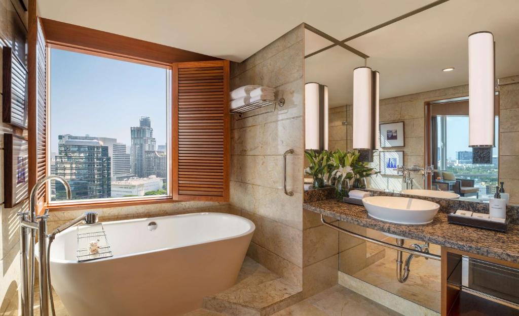a bathroom with a tub and two sinks and a window at Conrad Bangkok in Bangkok