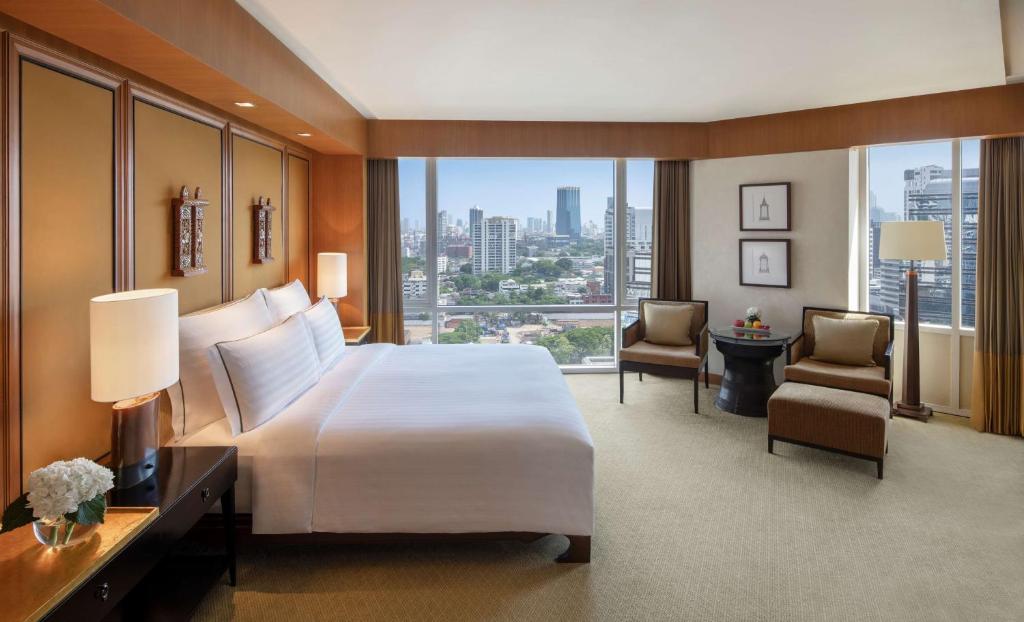 a hotel room with a large bed and a large window at Conrad Bangkok in Bangkok