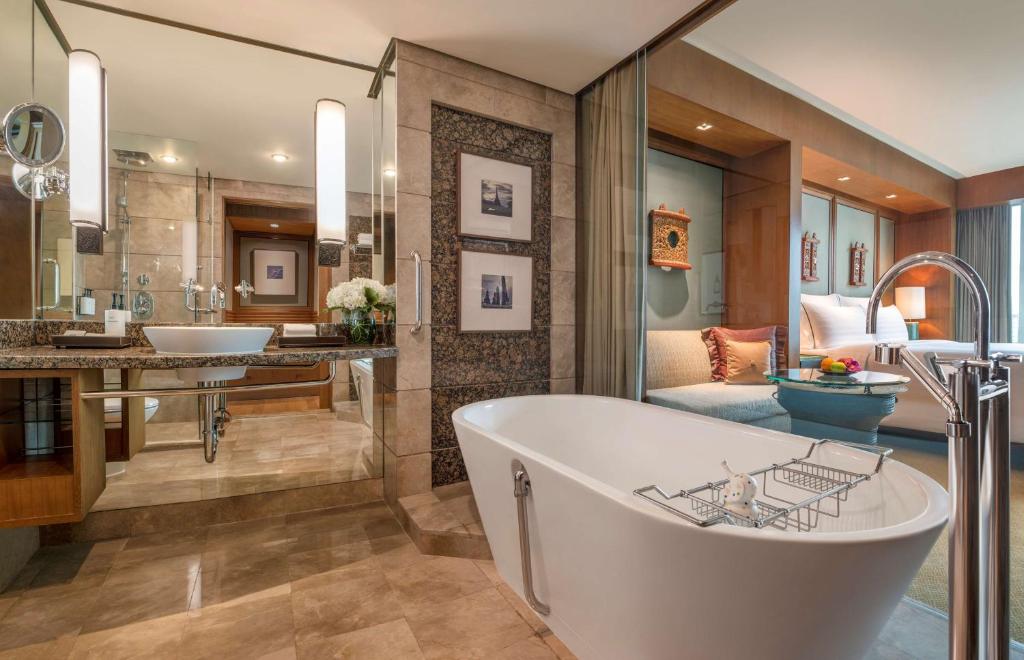 a bathroom with a tub and a bedroom at Conrad Bangkok in Bangkok