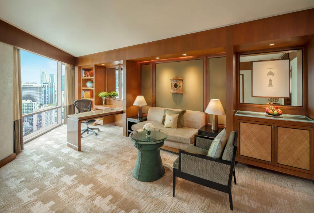 a living room with a couch and a desk at Conrad Bangkok in Bangkok
