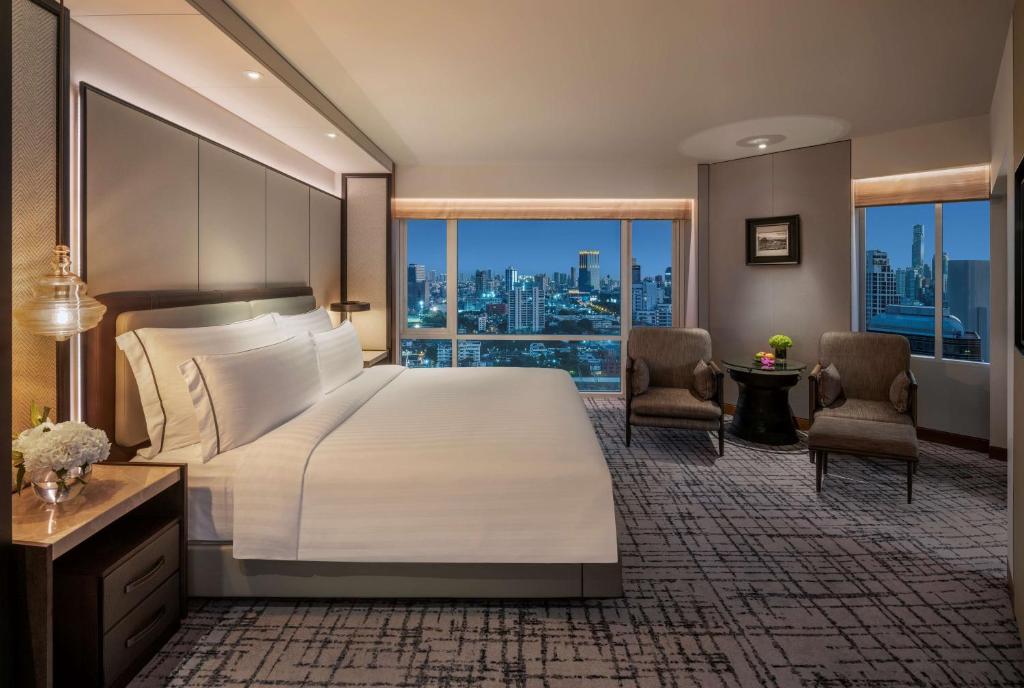 a bedroom with a large bed and a large window at Conrad Bangkok in Bangkok