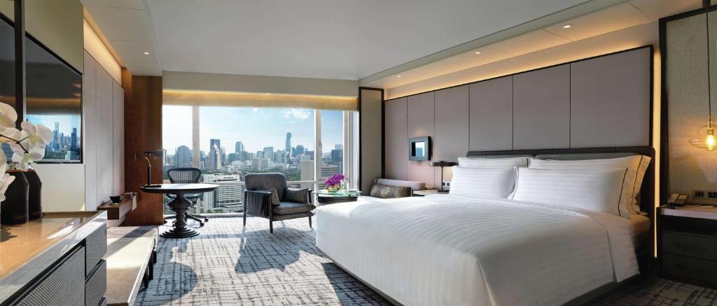 a bedroom with a large bed and a view of a city at Conrad Bangkok in Bangkok