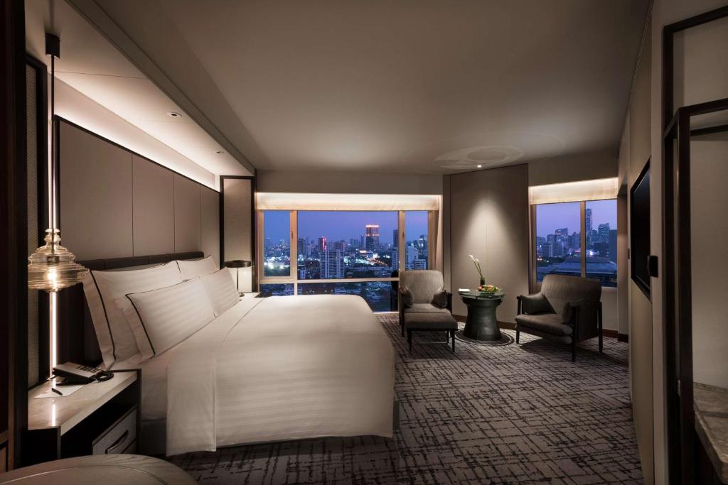 a bedroom with a bed and a view of a city at Conrad Bangkok in Bangkok