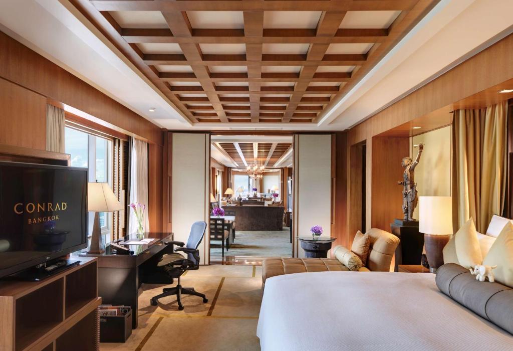 a hotel room with a bed and a living room at Conrad Bangkok in Bangkok