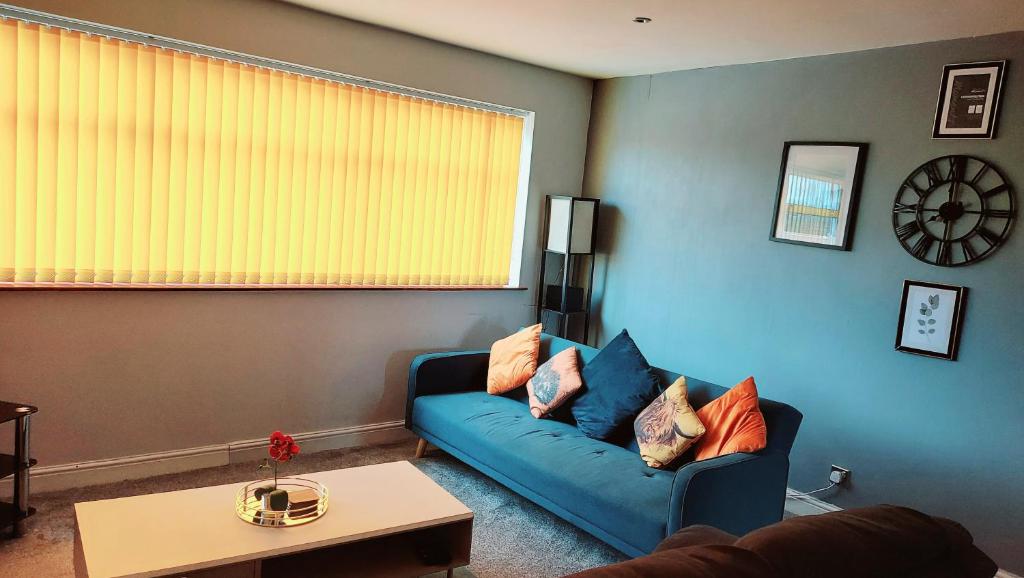 a living room with a blue couch and a table at HILLTOP PLACE Suites Near Doncaster RaceCourse in Doncaster