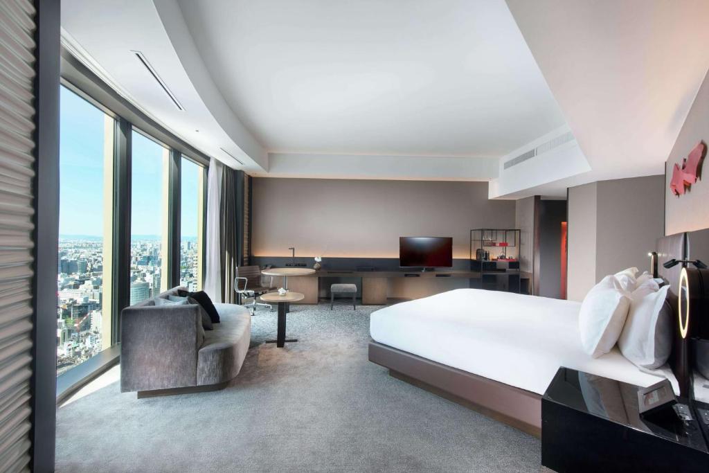 a hotel room with a large bed and a desk at Conrad Osaka in Osaka