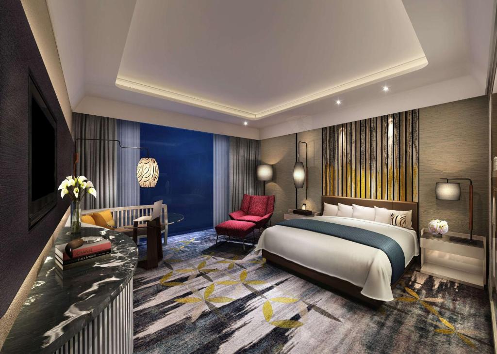 DoubleTree by Hilton Ahmedabad في أحمد آباد: غرفة نوم بسرير كبير وكرسي احمر