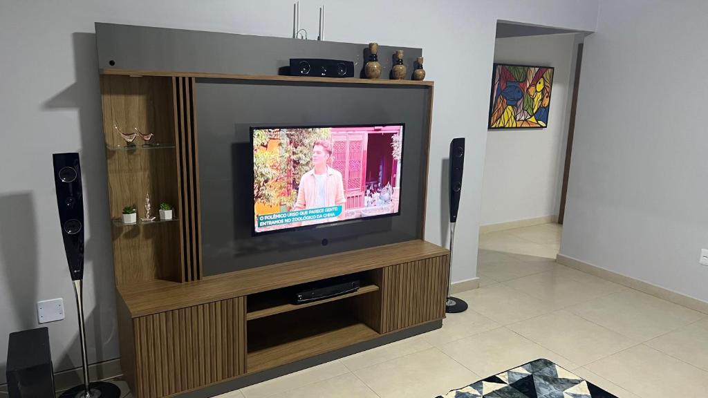 uma televisão de ecrã plano num centro de entretenimento em madeira em Linda casa em condomínio fechado em Brasília