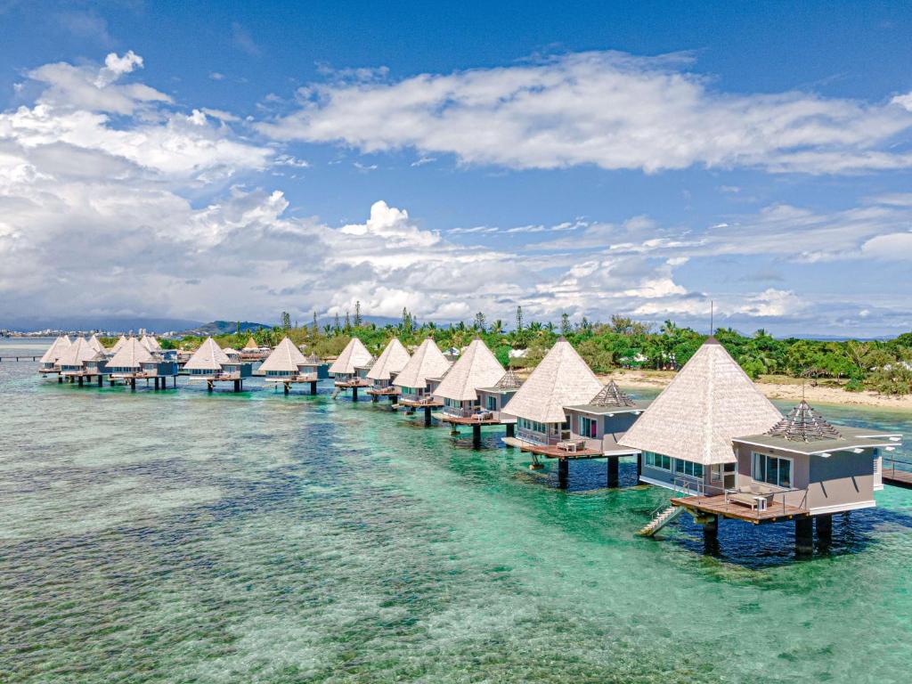 une rangée de bungalows sur pilotis dans l'eau dans l'établissement DoubleTree by Hilton Noumea Ilot Maitre Resort, à Ilot Maitre