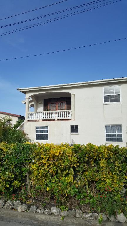 une maison blanche avec un balcon au-dessus d'une haie dans l'établissement Jazz apartment, à Christ Church