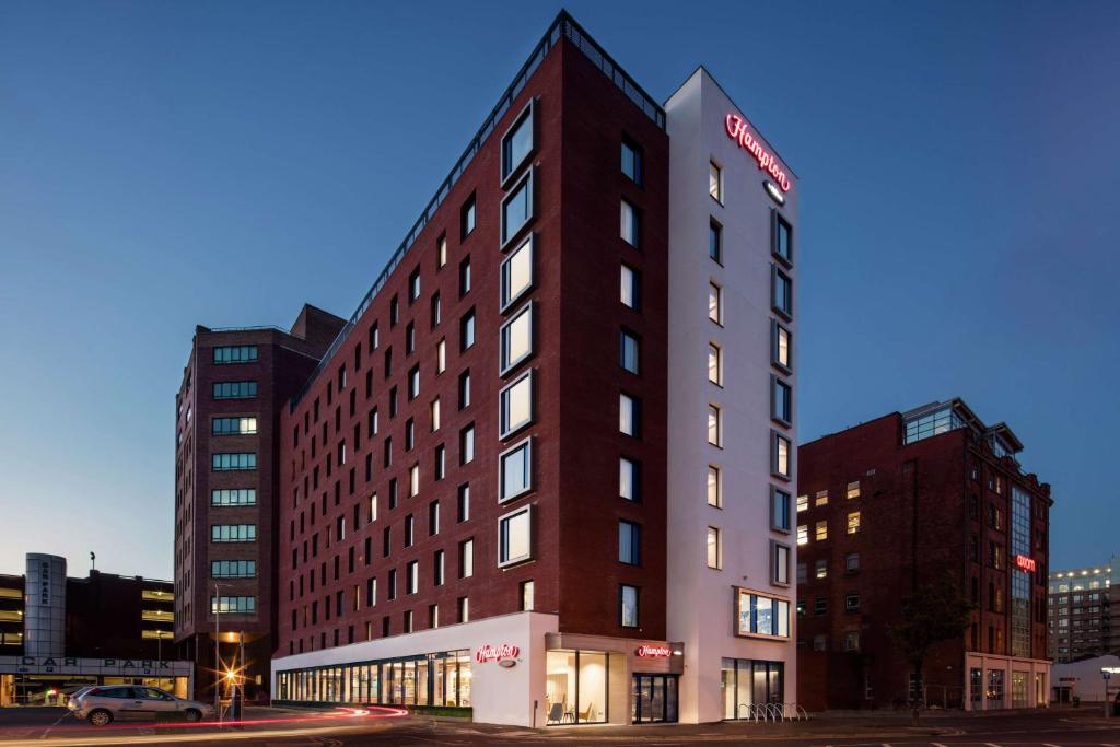 a tall red building with a sign on it at Hampton By Hilton Belfast City Centre in Belfast