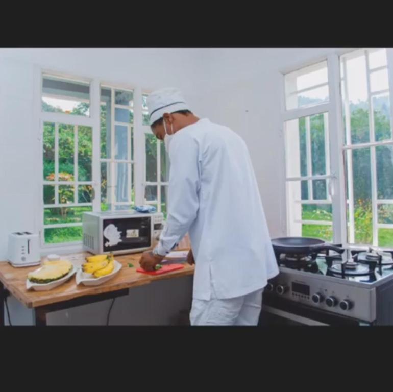 un hombre en una cocina preparando comida en una tabla de cortar en Maisondulac7 en Rubavu