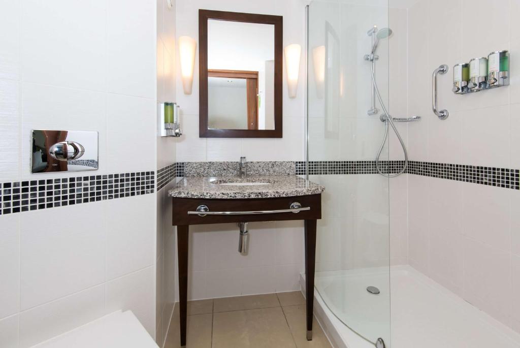 a bathroom with a sink and a shower and a mirror at Hampton by Hilton Birmingham Jewellery Quarter in Birmingham
