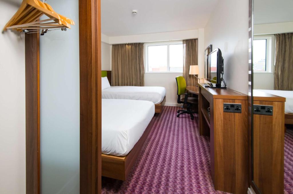 a hotel room with two beds and a desk and a television at Hampton by Hilton Birmingham Jewellery Quarter in Birmingham