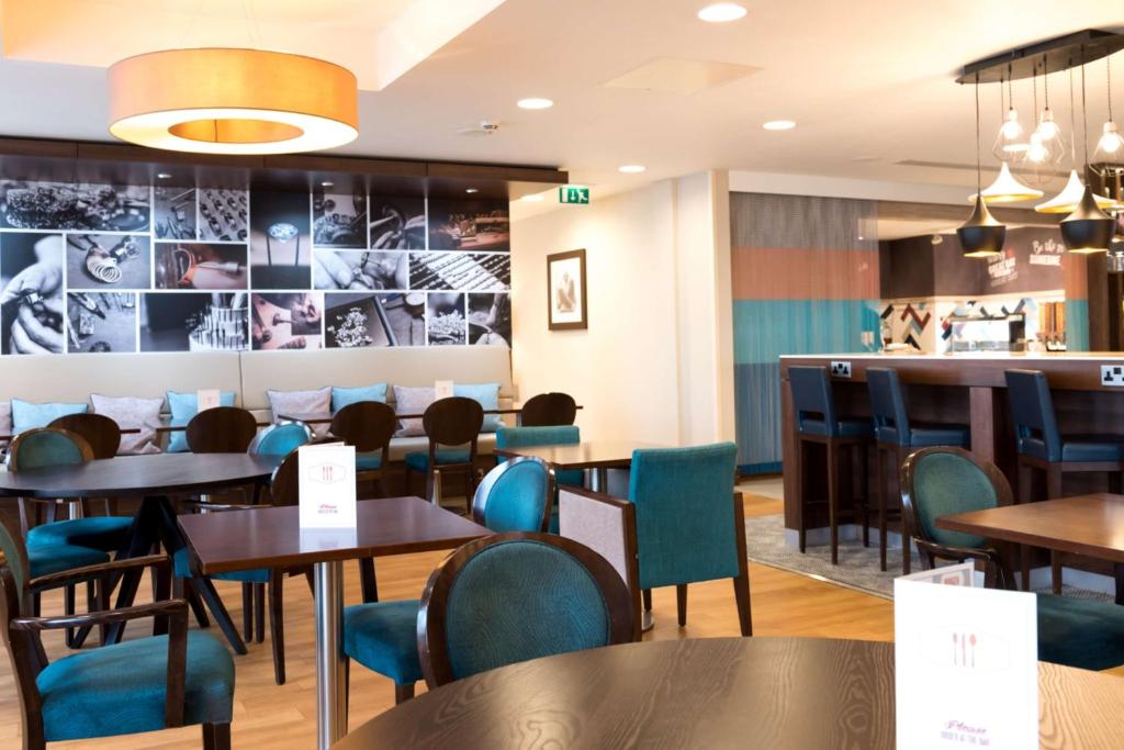 a restaurant with tables and chairs and a bar at Hampton by Hilton Birmingham Jewellery Quarter in Birmingham