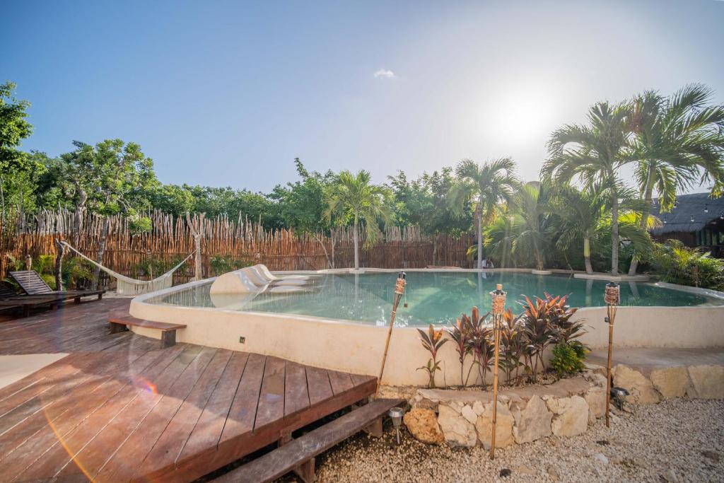 una gran piscina con una terraza de madera junto a ella en SelvaLuz Tulum Resort & Spa, en Tulum