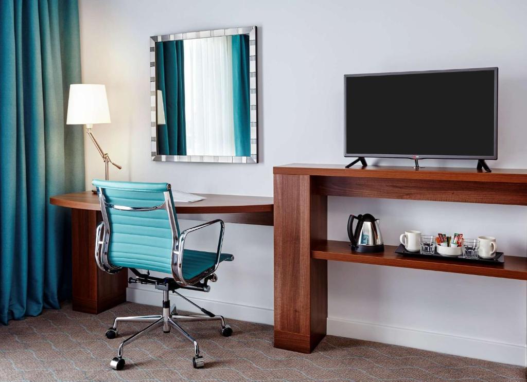 a room with a desk and a chair and a television at Hampton by Hilton Bournemouth in Bournemouth