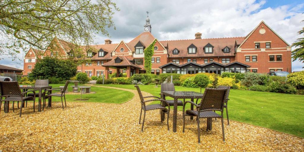 um grupo de cadeiras e mesas em frente a um edifício em DoubleTree by Hilton Stratford-upon-Avon, United Kingdom em Stratford-upon-Avon