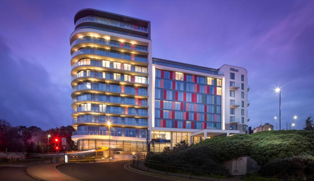 a large building with red and blue windows at night at Hilton Bournemouth in Bournemouth