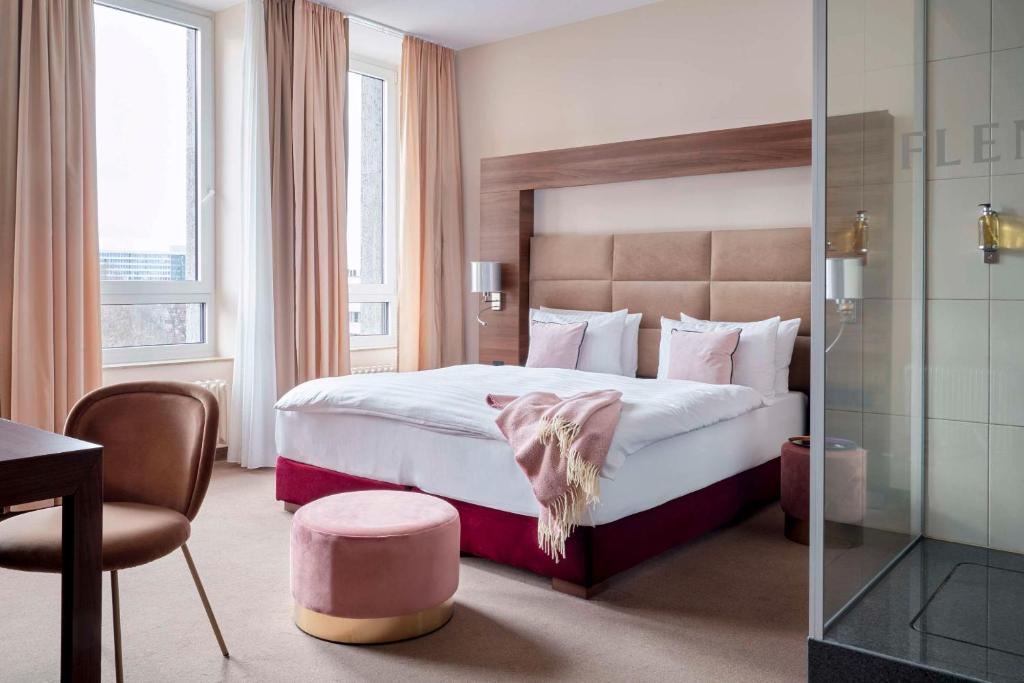 Cette chambre comprend un grand lit et une chaise. dans l'établissement Flemings Selection Hotel Frankfurt-City, à Francfort-sur-le-Main