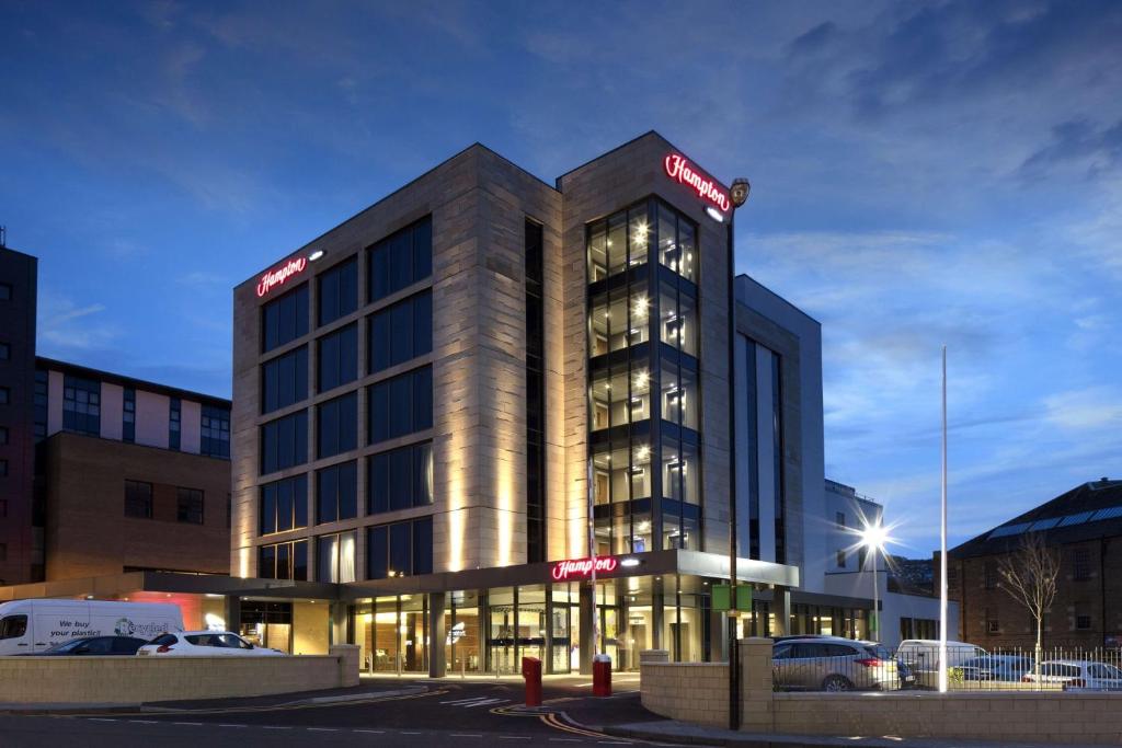 un edificio illuminato con macchine parcheggiate di fronte di Hampton by Hilton Dundee a Dundee