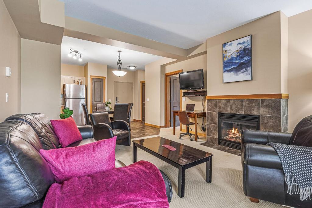 a living room with leather furniture and a fireplace at Spacious King Bed with Pool & Hot Tubs in Canmore